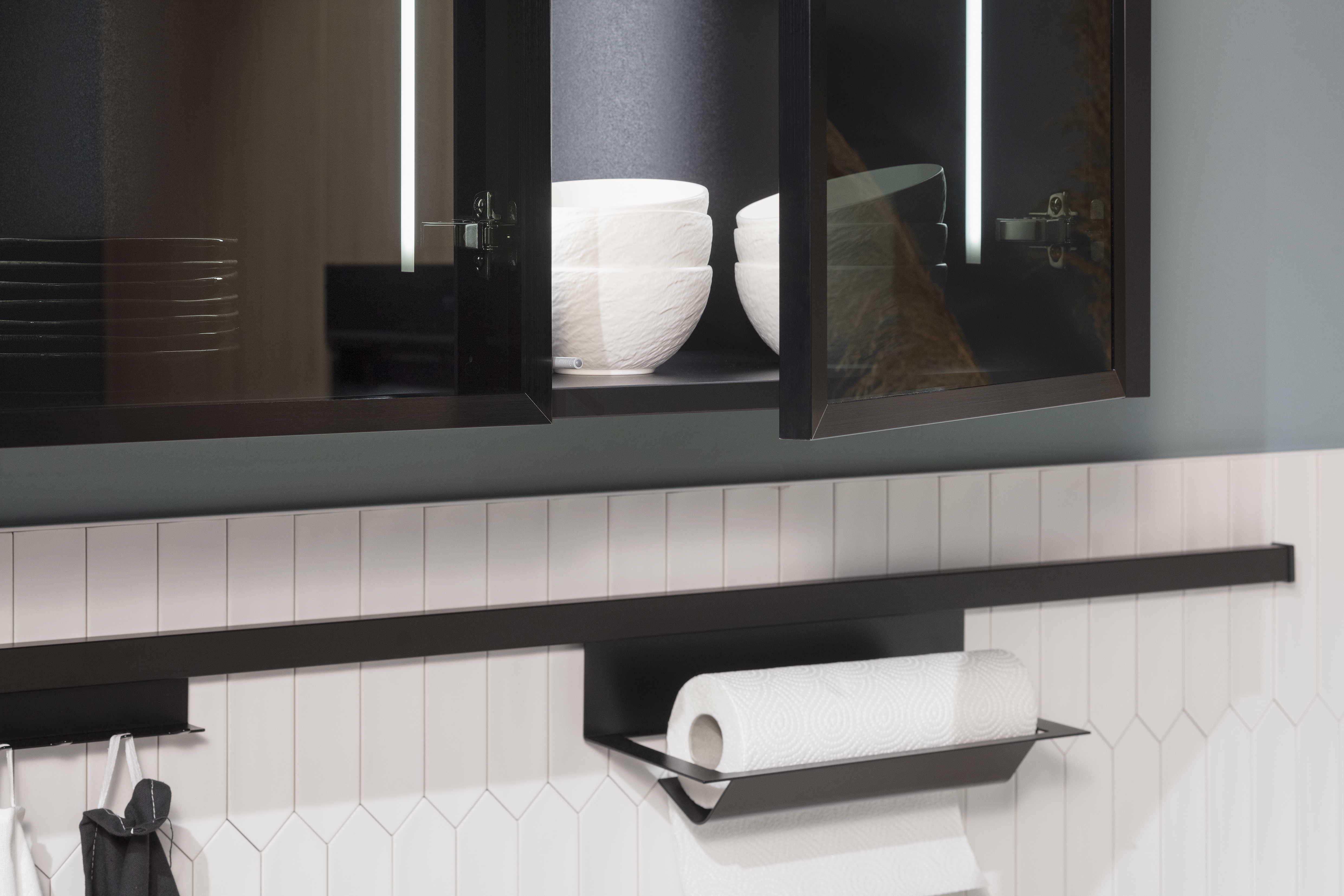 Hängeschrank mit Glasfronten und Reling auf Fliesenspiegel. 