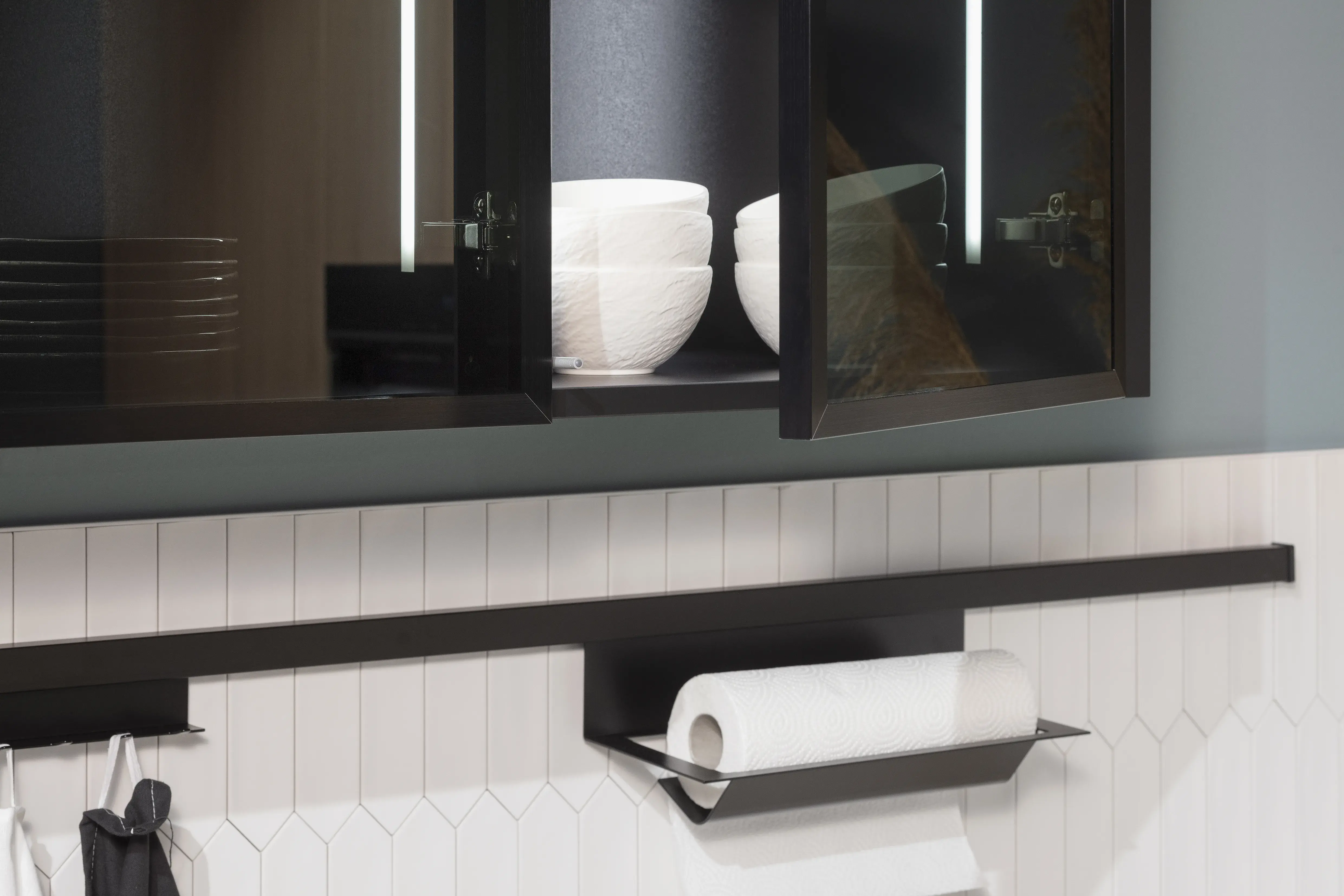 Hängeschrank mit Glasfronten und Reling auf Fliesenspiegel. 