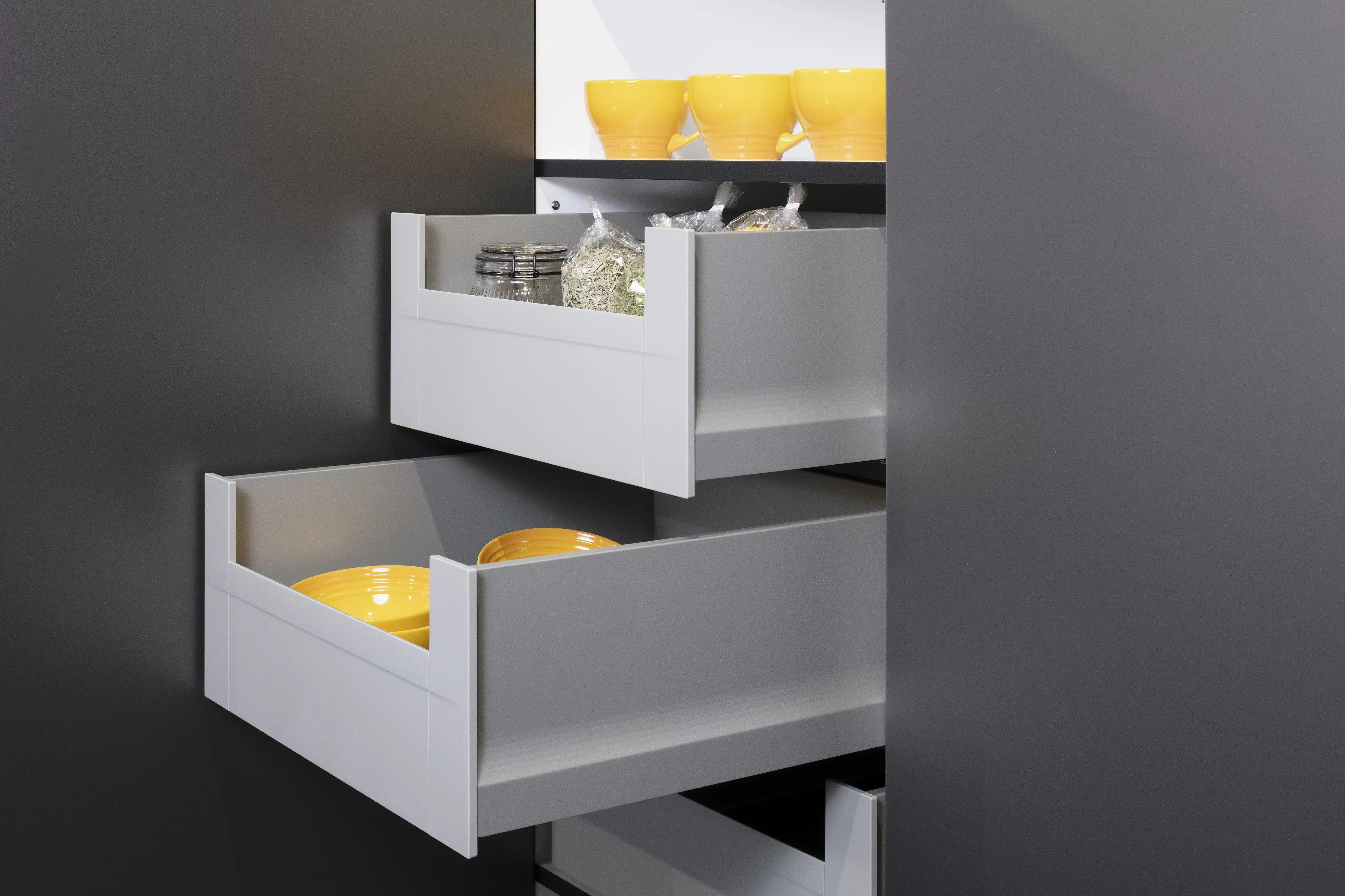 Concept130ART Front: SMART-GL Sandgrau metallic APL: SMART-GL Carbon metallic Geräte Blaupunkt Armatur und Spüle: Franke  Features: Insellösung mit Thekenfunktion mit Schubladen, Teppanyakiaufsatz für Kochfeld, Schubladen in Silber, Schubladen mit Griffmulde, Nischenlösung in Blau mit Regalfunktion.